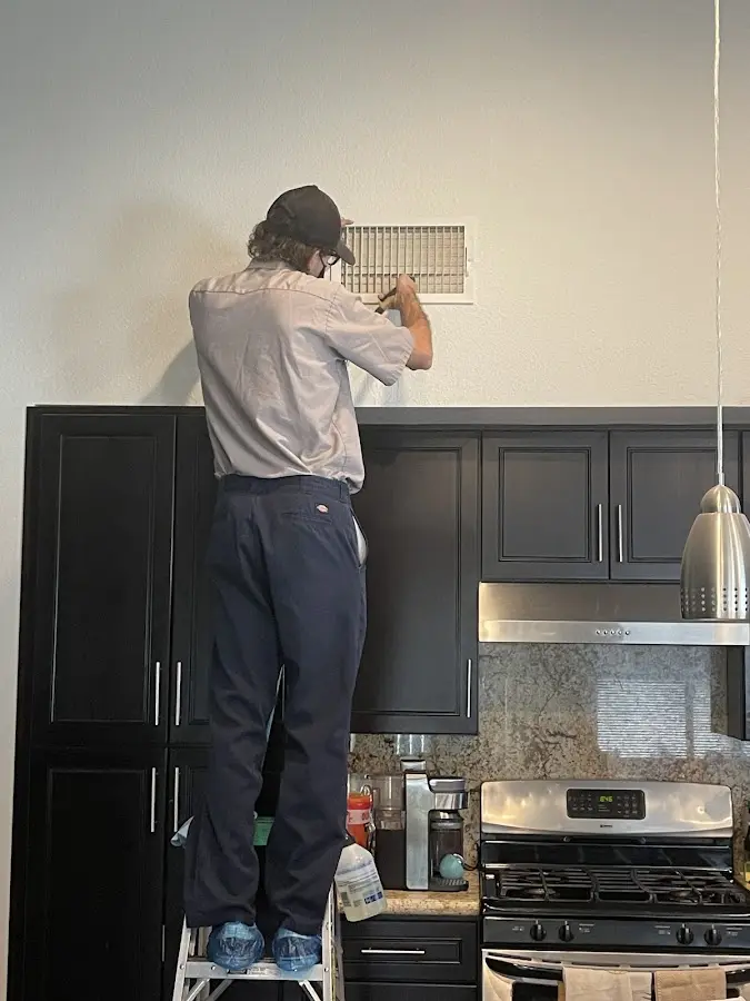 Technician inspecting an air vent during HVAC service in North Highlands